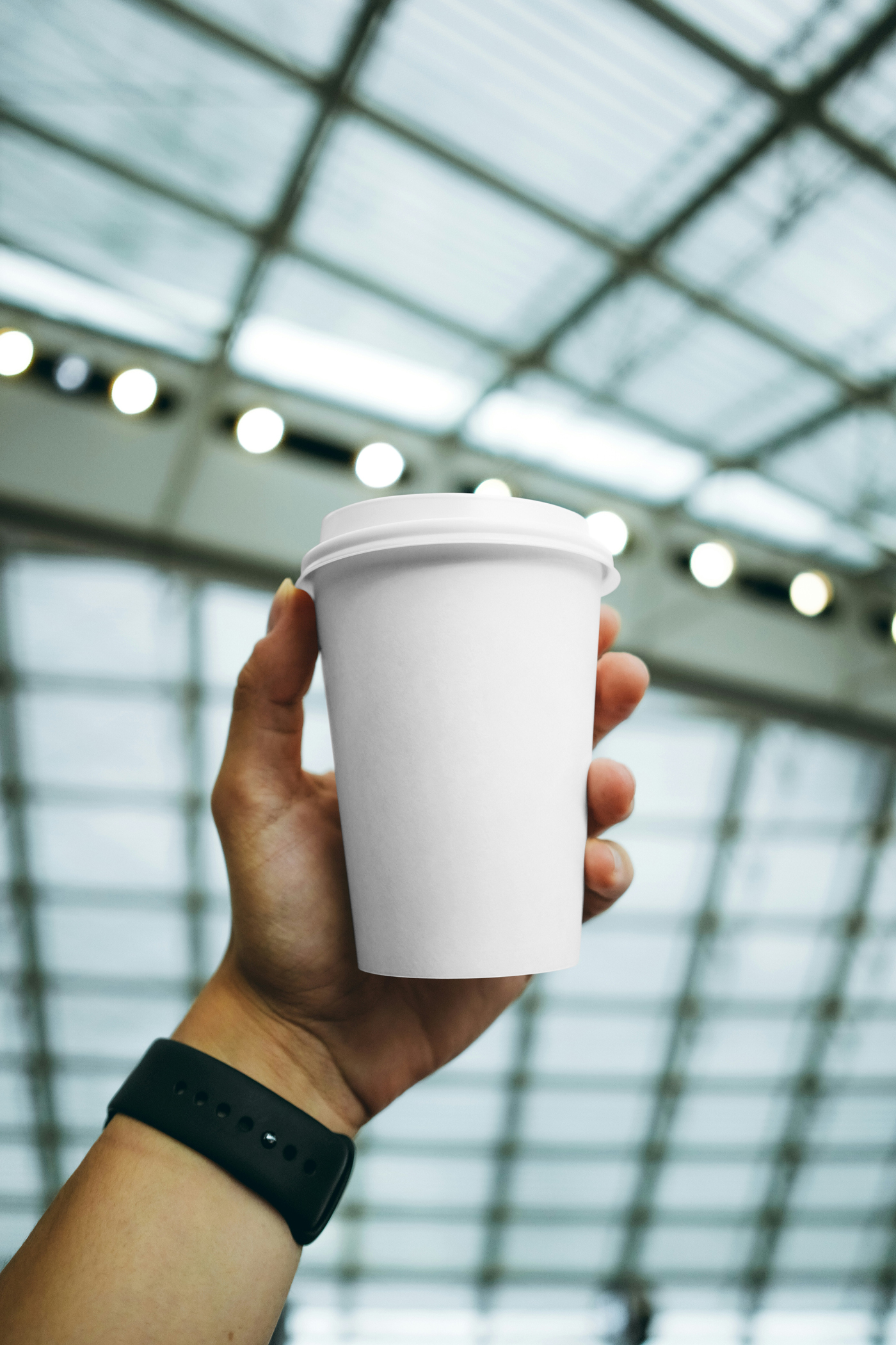 Front view of a white coffee cup mockup held by a man's hand.