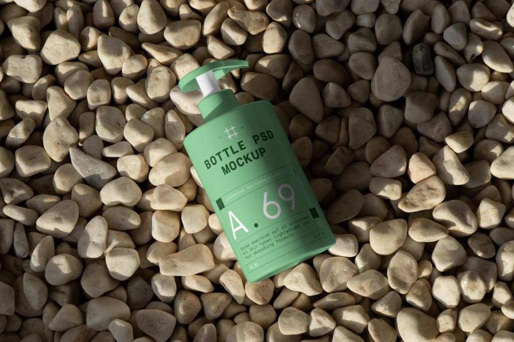 View from above, green cosmetic bottle mockup with dark green and white typography designs lying on the rocks.