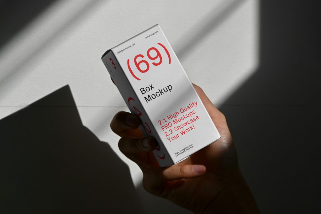 Front view of a white box mockup with a red and black strong typography design held by a woman's hand.