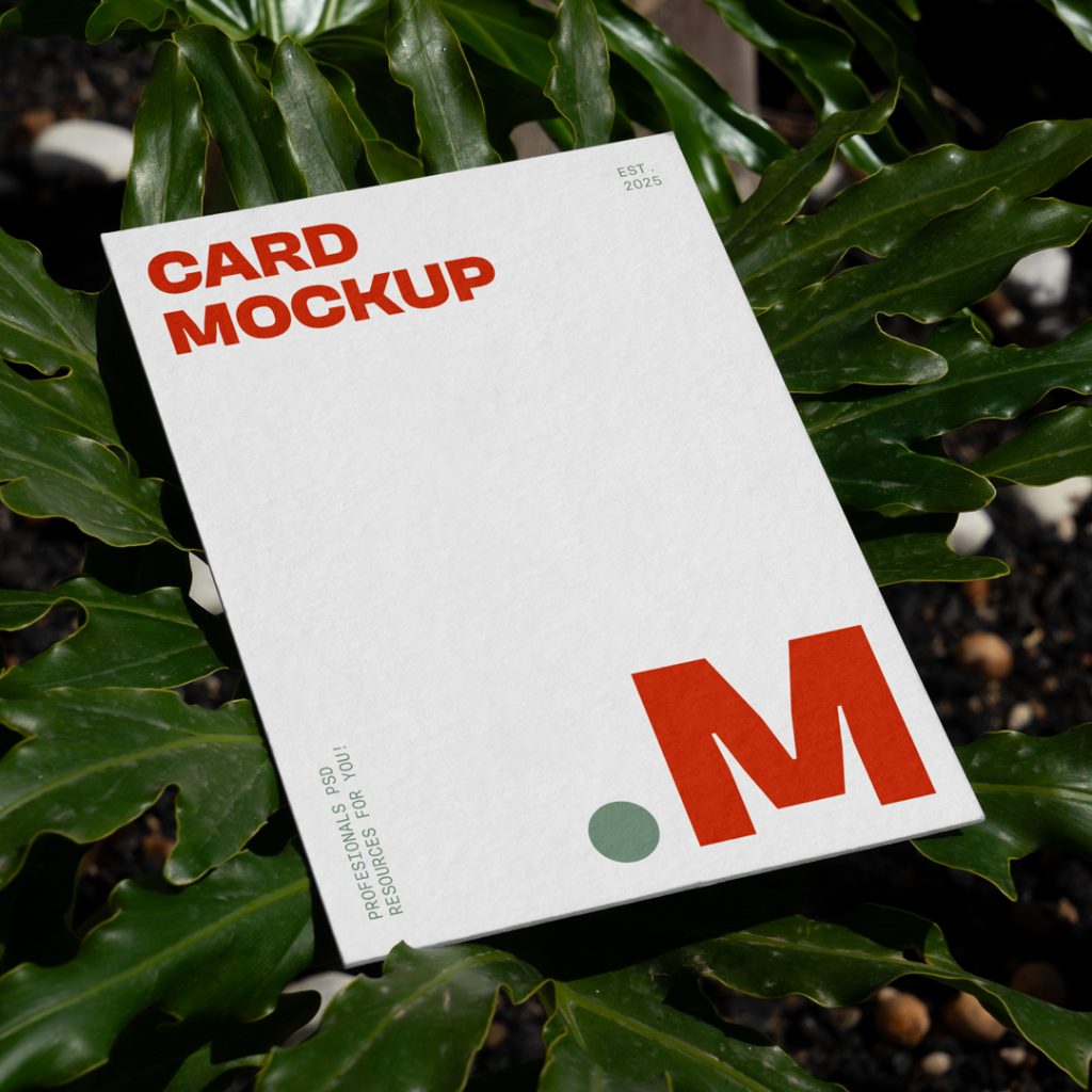 View from above, card mockup with red and green typography design lying between a tropical flower.