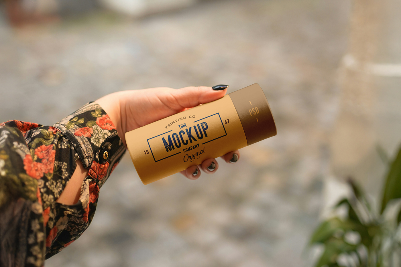 Front view of a beige tube mockup with a vintage typography design held by a woman's hand.