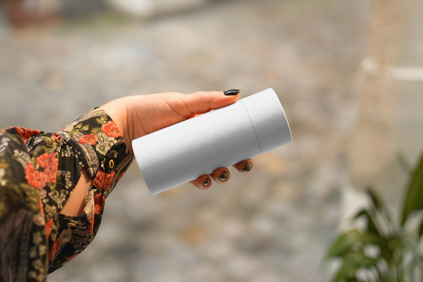 Front view of a white tube mockup held by a woman's hand.