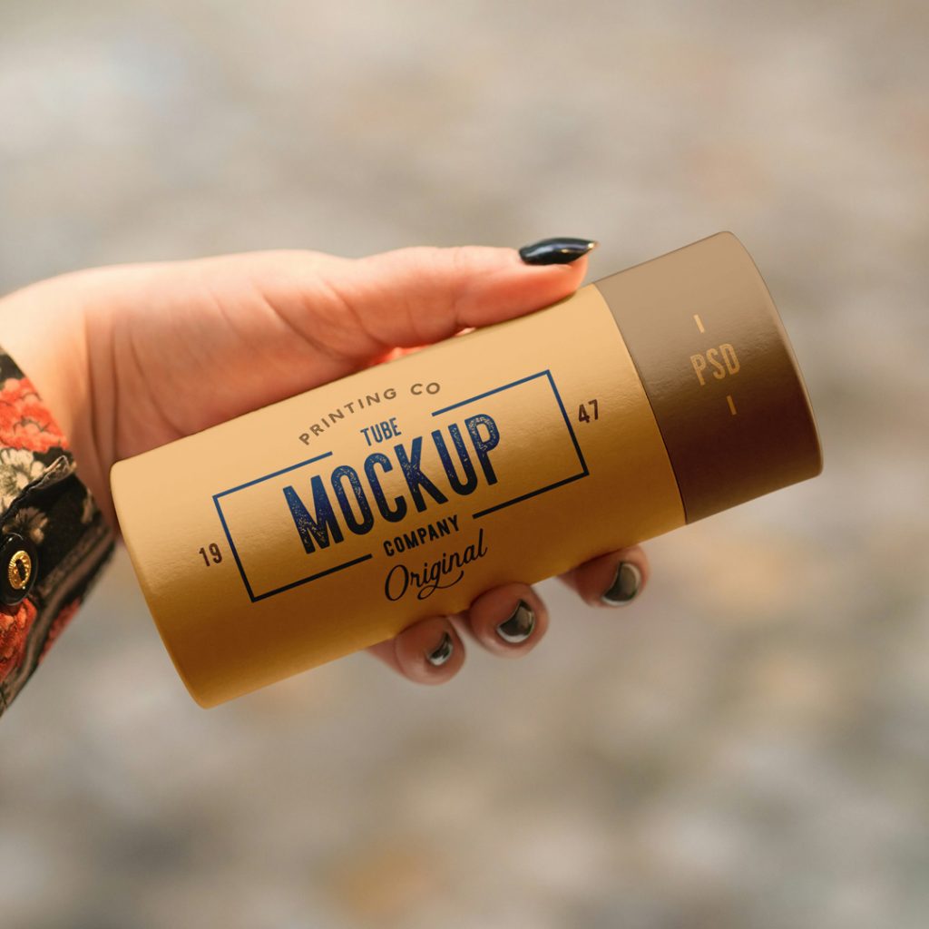 Front view of a beige tube mockup with a vintage typography design held by a woman's hand.