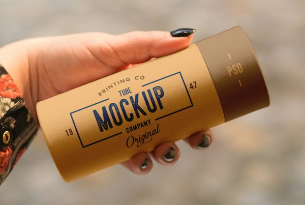 Front view of a beige tube mockup with a vintage typography design held by a woman's hand.