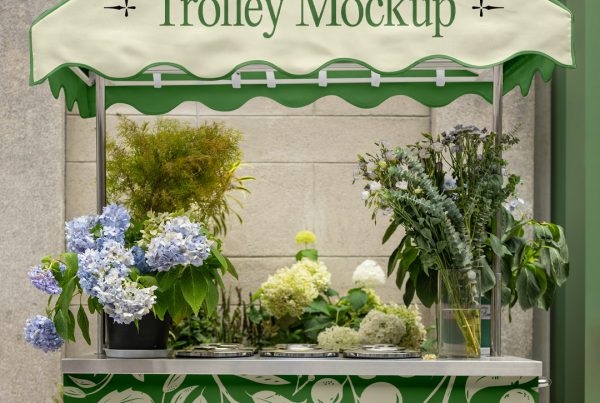 Front view, trolley mockup in beige and green with a serif typography design and flower pattern standing in front of the concrete wall.