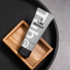 View from above, a Cosmetic Tube Mockup with delicate cosmetic design in black, white, and gray colors, lying on a wooden box, which lies on a black tray.