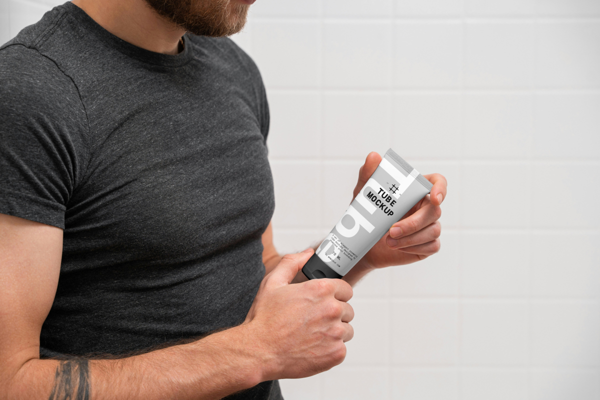 The front view presents men holding a cosmetic tube mockup with a delicate cosmetic design in black, white, and gray colors in both hands.