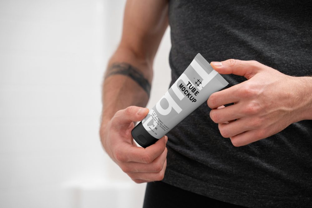 Front view, close up view of men holding a Cosmetic Tube Mockups with delicate cosmetic design in black, white, and gray colors in both hands.