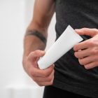 Front view, close up view of men holding a white Cosmetic Tube Mockups in both hands.