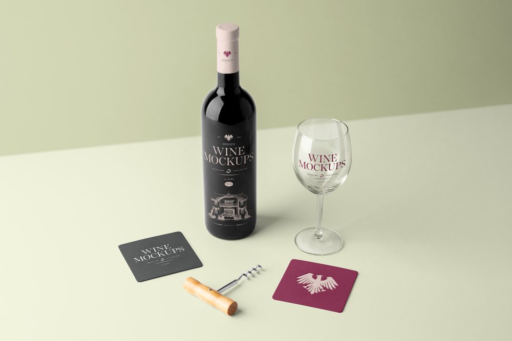 View from above, scene from Studio Wine Mockups of a standing black wine bottle with pink typography design, transparent wine glass with claret typography design, and two paper pads on the bright green background.