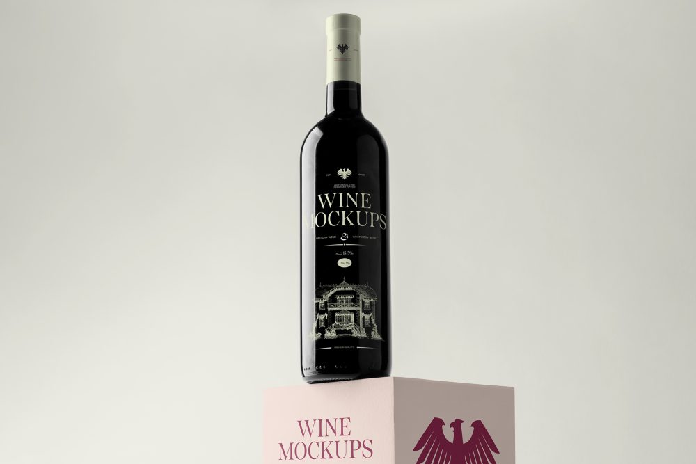Front view, scene from Studio Wine Mockups of a black wine bottle with a bright green design standing on the pink cubic with a claret design on the bright gray background.