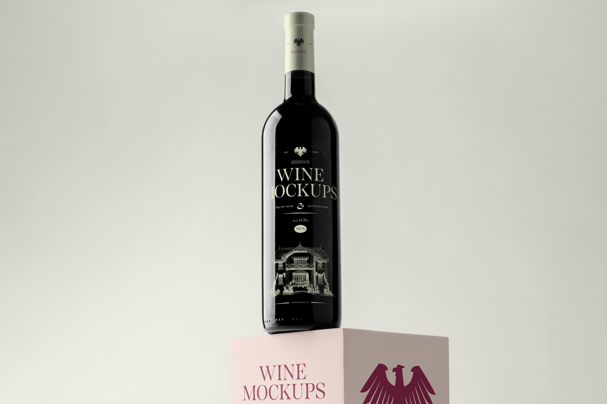 Front view, scene from Studio Wine Mockups of a black wine bottle with a bright green design standing on the pink cubic with a claret design on the bright gray background.