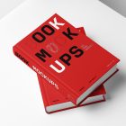 Top view at an angle of two hardcover book mockups in PSD with bold typography design in black, gold, gray, and white colors lying on top of each other for editorial and publishing design.