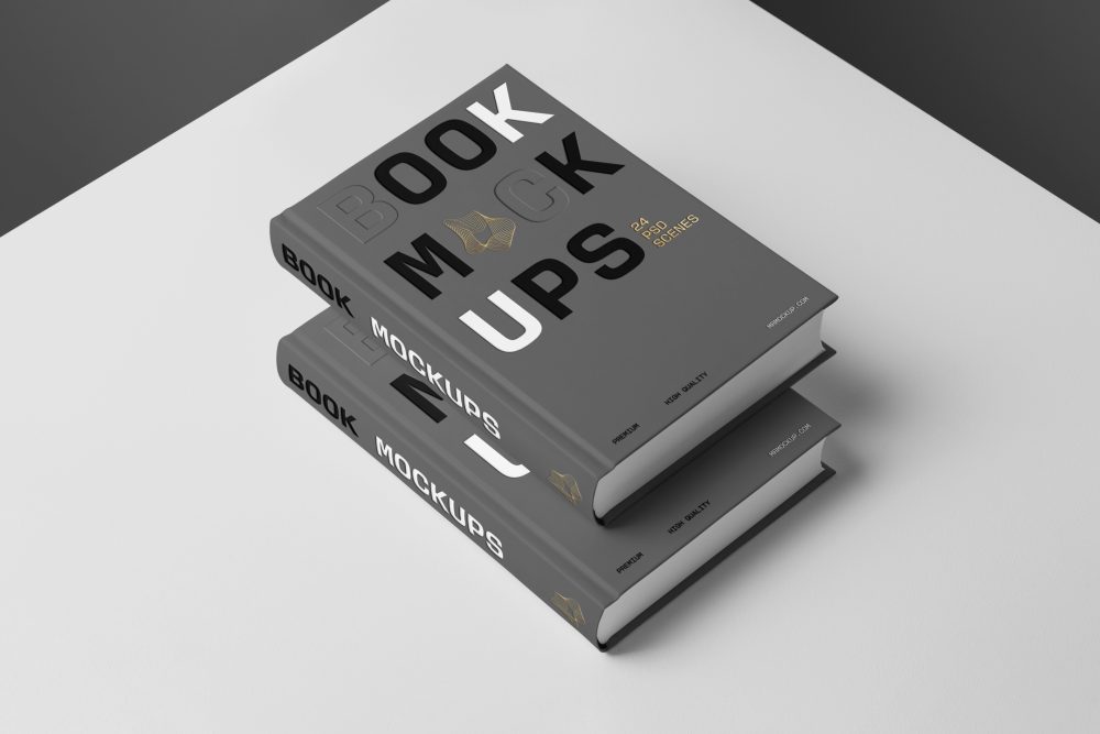 Top view at an angle of two hardcover book mockups in PSD with bold typography design in black, gold, gray, and white colors lying on top of each other for editorial and publishing design.