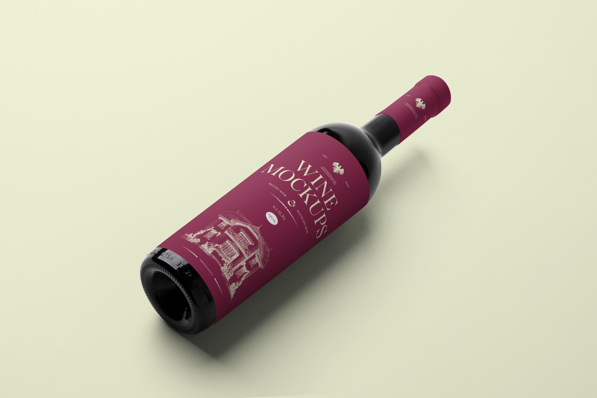 View from above the scene from Studio Wine Mockups of a black wine bottle with a claret label and typography design lying on the bright green background.