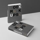 View from above, two hardcover book mockups with bold typography design in black, gold, gray, and white colors are located on the white background in perspective view.