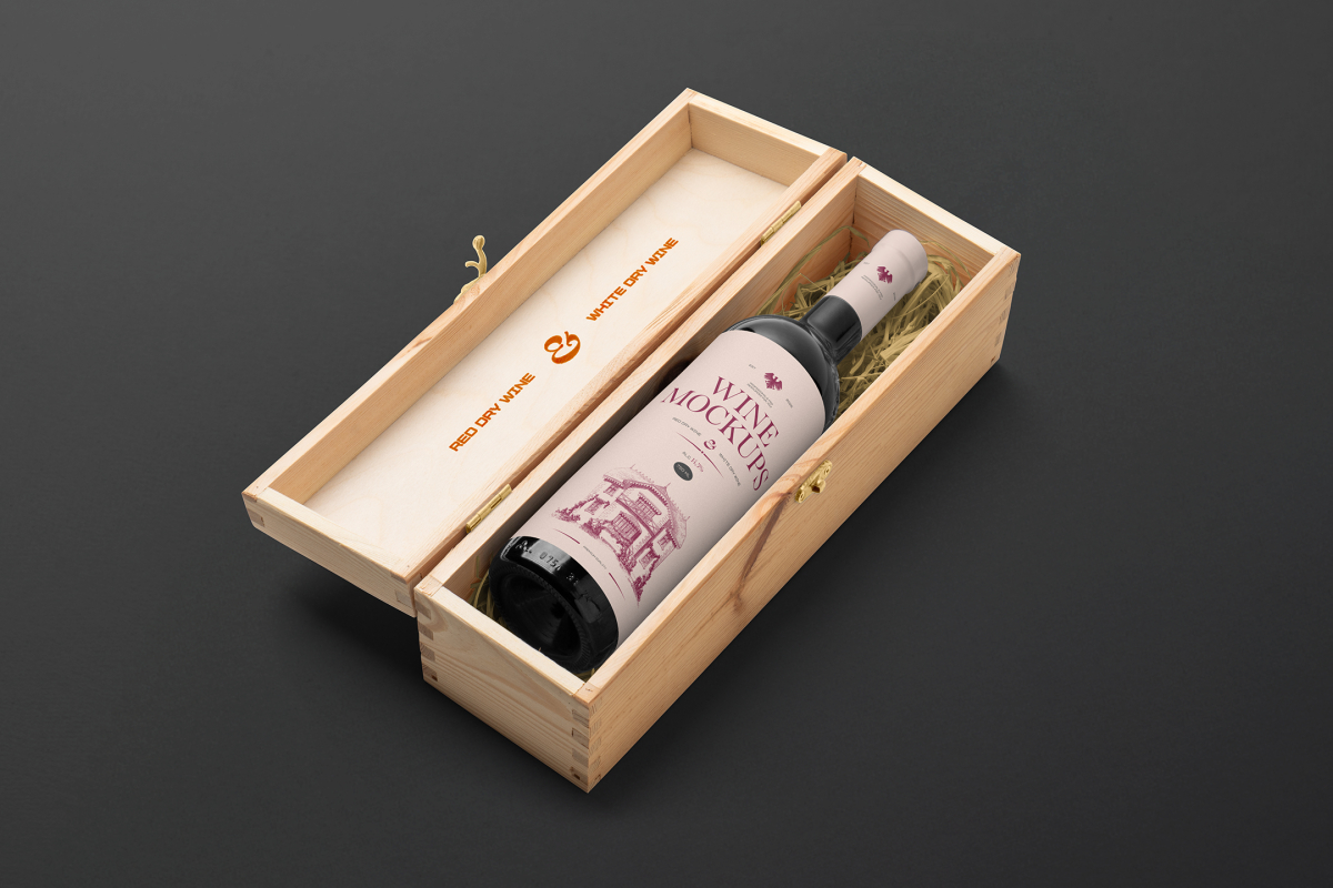 View from above, the scene from Studio Wine Mockups of an open wooden box with a black bottle of wine inside with a pink label and typography design lying on the black background.