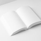 View from above, a white open softcover book mockup lying on the white background in perspective view.