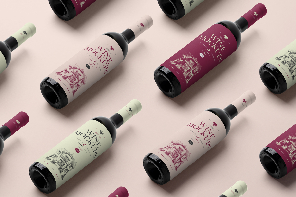 View from above the scene from Studio Wine Mockups of twelve black wine bottles with a pink, green, and claret label color and typography design lying on the pink background.