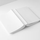 View from above, a white softcover book mockup turned upside down lying on the white background in perspective view.