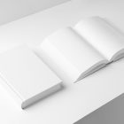 View from above, two white hardcover book mockups lying on the white background in perspective view.