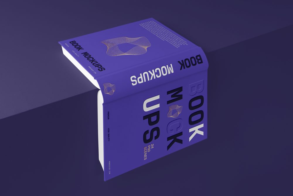 View from above, an open hardcover book mockup with bold typography design in black, gold, purple, and white colors lying on the edge of the purple cube.