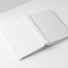 View from above, a white hardcover book mockup turned upside down lying on the white background in perspective view.