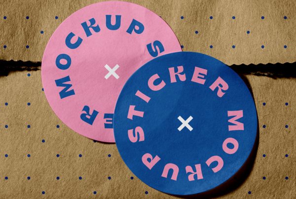 View from above, two rounded Sticker Mockup with slab typography design in pink and navy blue colors are glued to the craft paper bag.