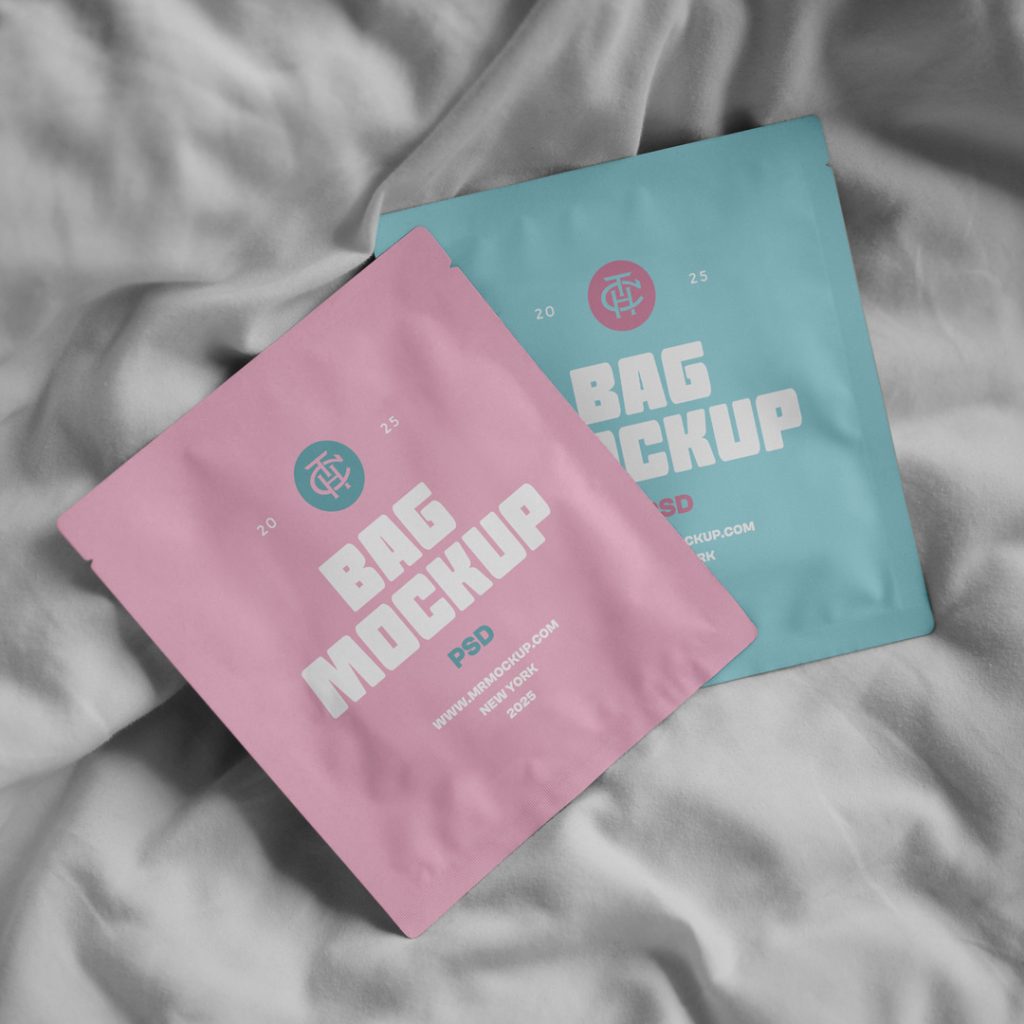 View from above, two cosmetic bag mockups in pastel pink and pastel blue colors lying on white bedding.