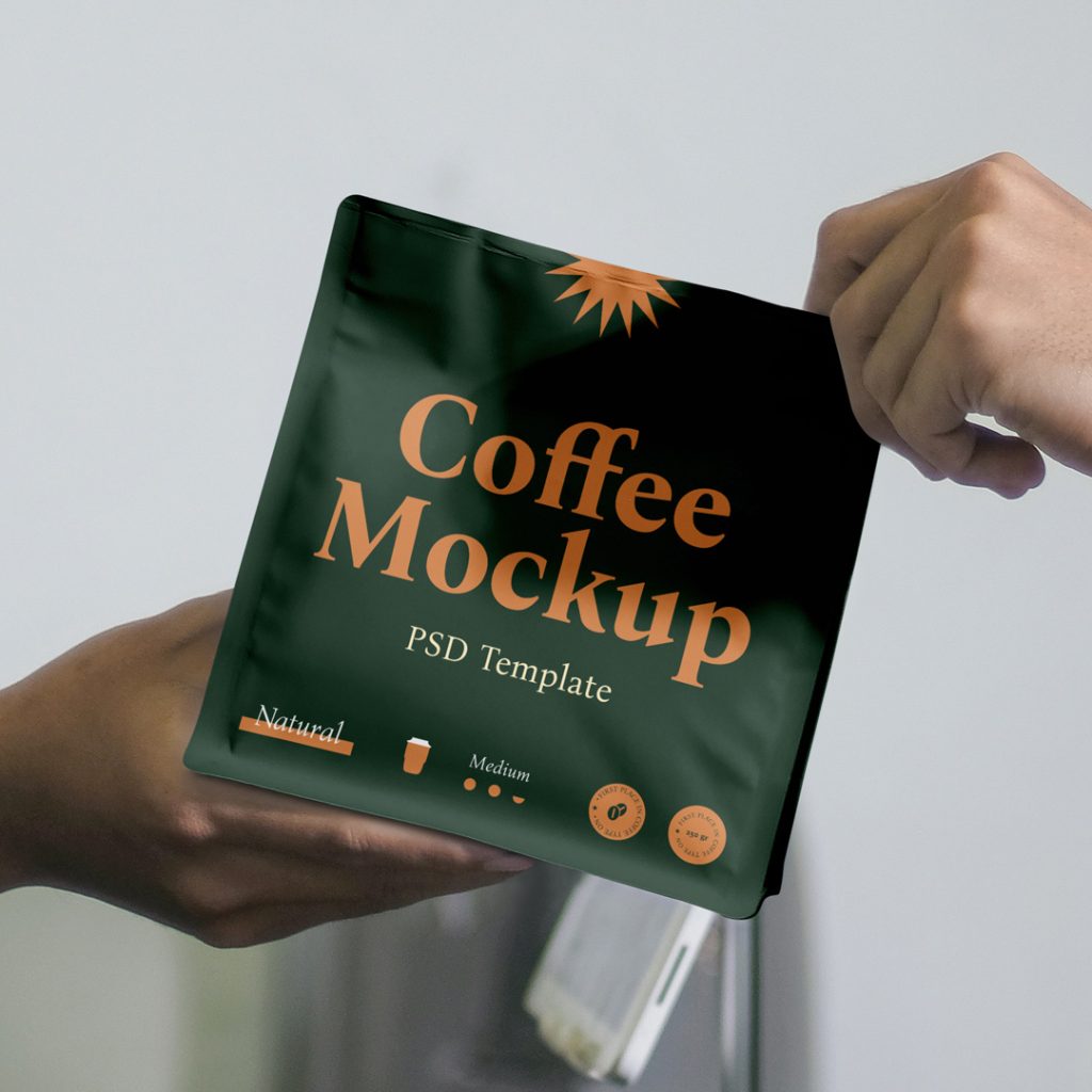 In the front view, a green plastic coffee bag mockup with strong typography design is held by two persons in the kitchen background.