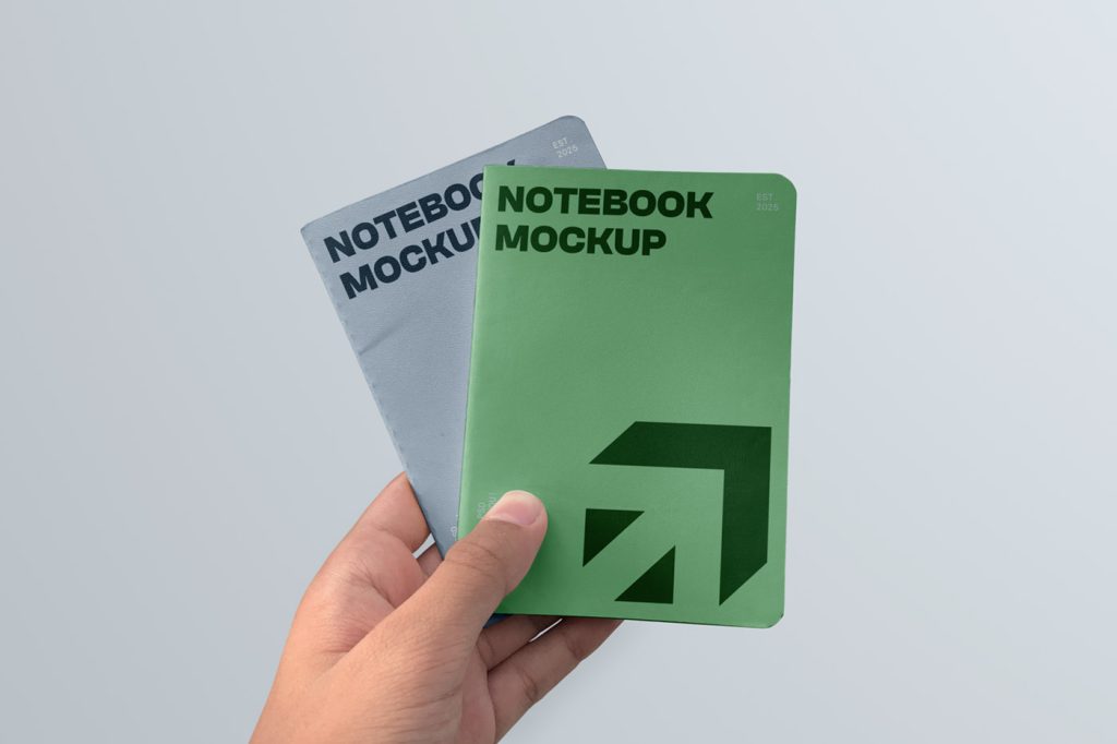 In the front view, two small notebook mockups in green and blue color and strong typography design are held by a man's hand on the blue background.