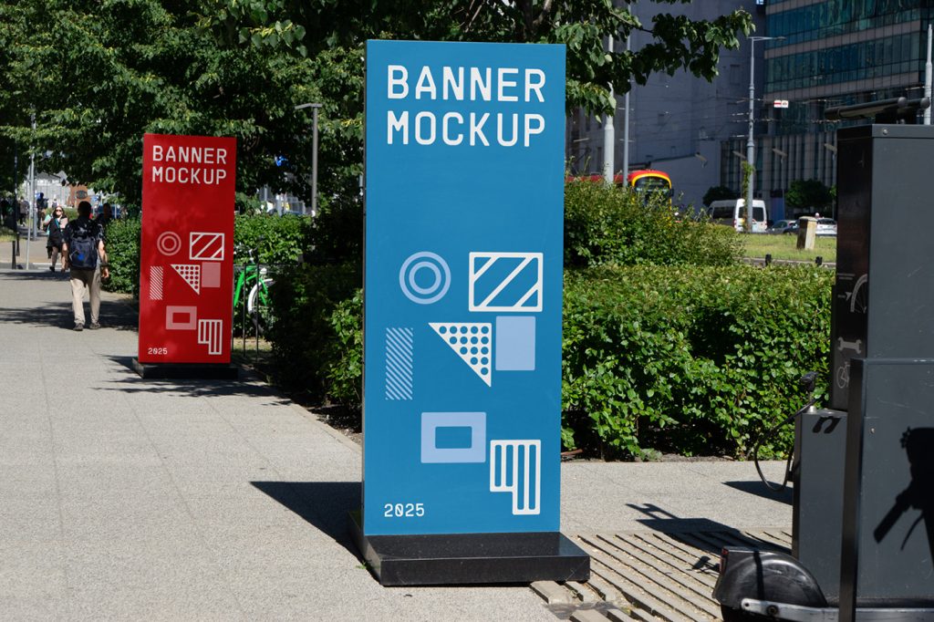 Front view, two city banner mockups in red and blue colors with geometrical design standing on the sidewalk.