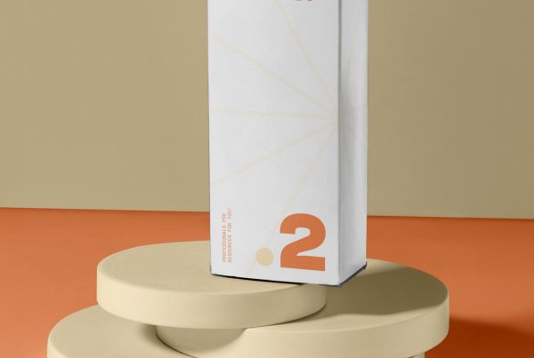 In the front view, a single white vertical box mockup with strong cosmetic design in cream and orange colors stands on the cream colored stand.