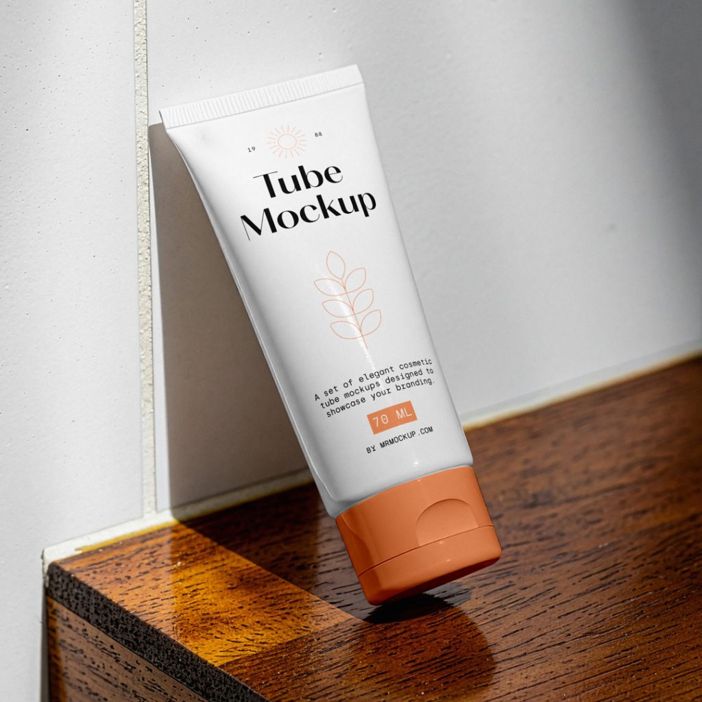 Front view, a cosmetic tube mockup with delicate cosmetic design in black and orange colors, standing on a wooden stool, based on the white wall in the brightly lit bathroom.