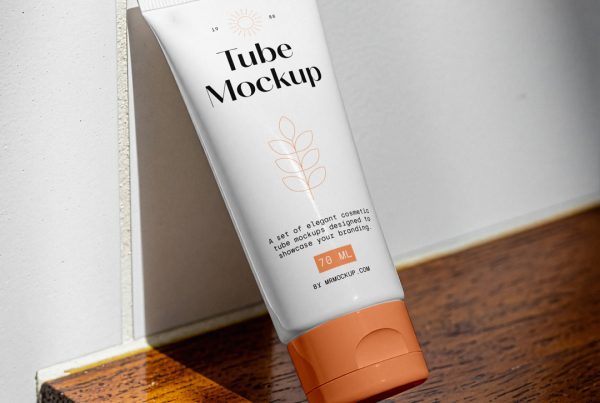 Front view, a cosmetic tube mockup with delicate cosmetic design in black and orange colors, standing on a wooden stool, based on the white wall in the brightly lit bathroom.