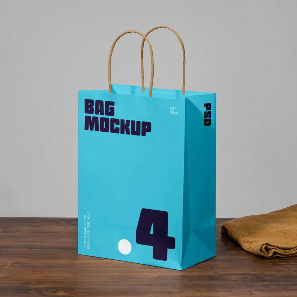 Front view blue shopping paper bag mockup with a strong typography design in white and navy standing on the wooden table.