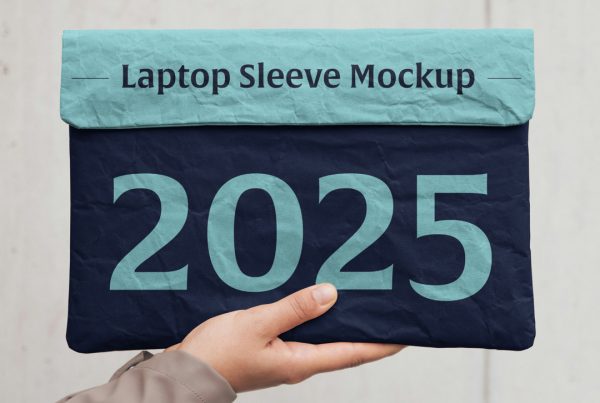 Front view, hand holding laptop sleeve mockup in two blue shades and classic typography design on the blurred wall background.