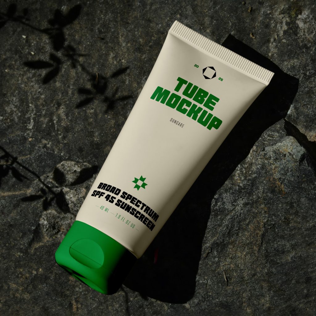 View from above, cosmetic tube mockup with typography design in black, green, and cream colors lying on the dark stone color.