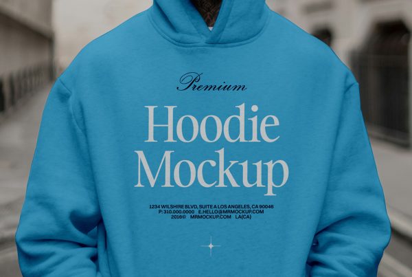 Front view, standing male model wearing a baby blue hoodie color mockup with a serif typography design against the city view.