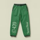 View from above, lying green sweatpants mockup with typography design on the bright studio background color from studio apparel mockups product.