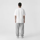 Front view, male model standing backward wearing a white t-shirt & grey sweatpants mockup against a white studio background from the studio apparel mockups product.