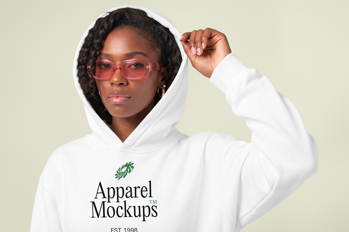 Front view of a Black female model wearing a white hoodie mockup standing against the bright studio background from studio apparel mockups product.