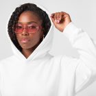 Front view of a Black female model wearing a white hoodie mockup standing against the white studio background from the studio apparel mockups product.