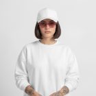 Front view of a female model wearing a white sweatshirt and white cap mockup standing against the white studio background from the studio apparel mockups product.