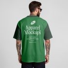 Front view, male model backward wearing a green t-shirt mockup with white typography design standing against a grey studio background from the studio apparel mockups product.