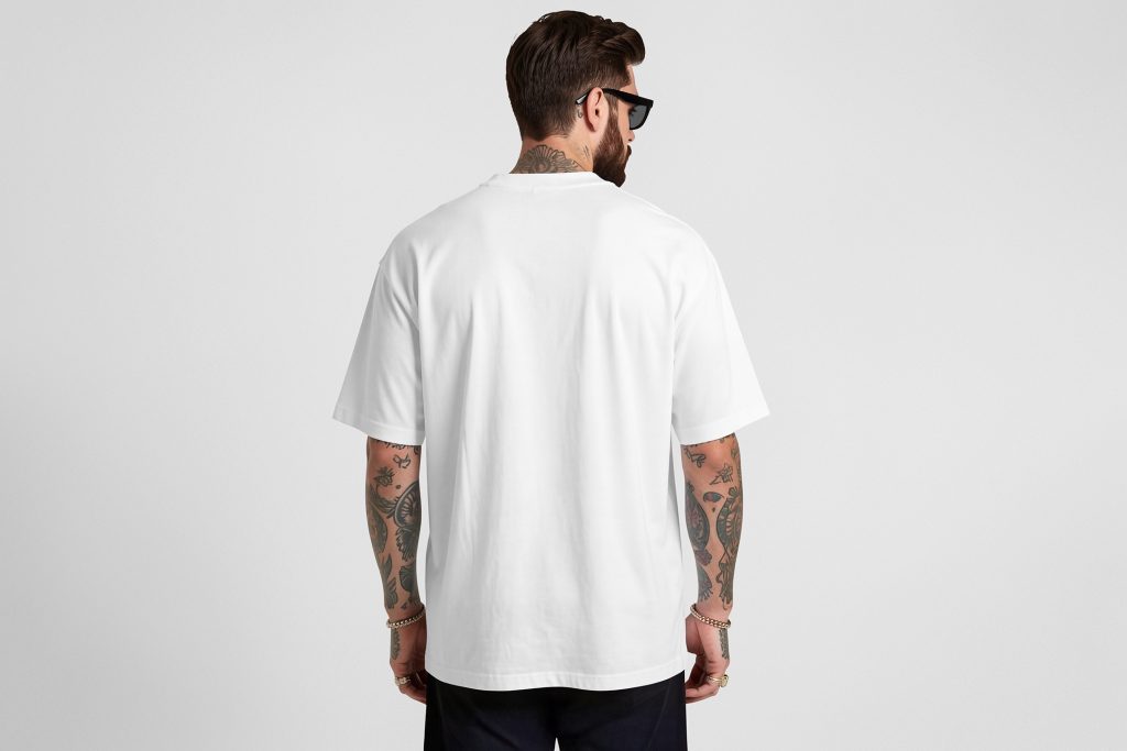 Front view, male model backward wearing a white t-shirt mockup standing against a white studio background from the studio apparel mockups product.