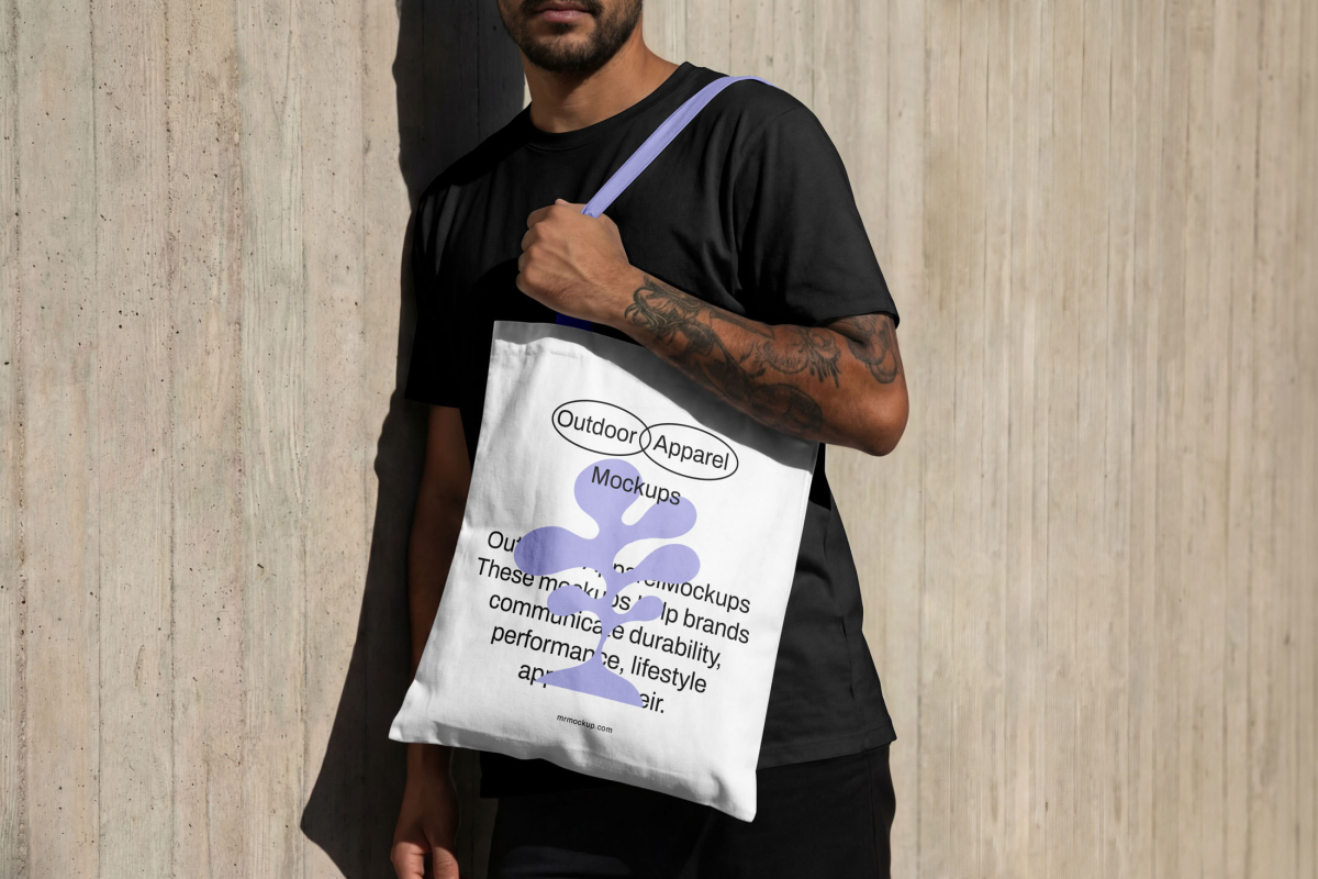 Male model presenting canvas bag mockup with purple handle from the Outdoor Apparel Mockups Vol.3 product.