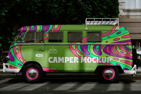Front view of hippie camper mockups on the side in colorful colors and white typography parked near the sidewalk.