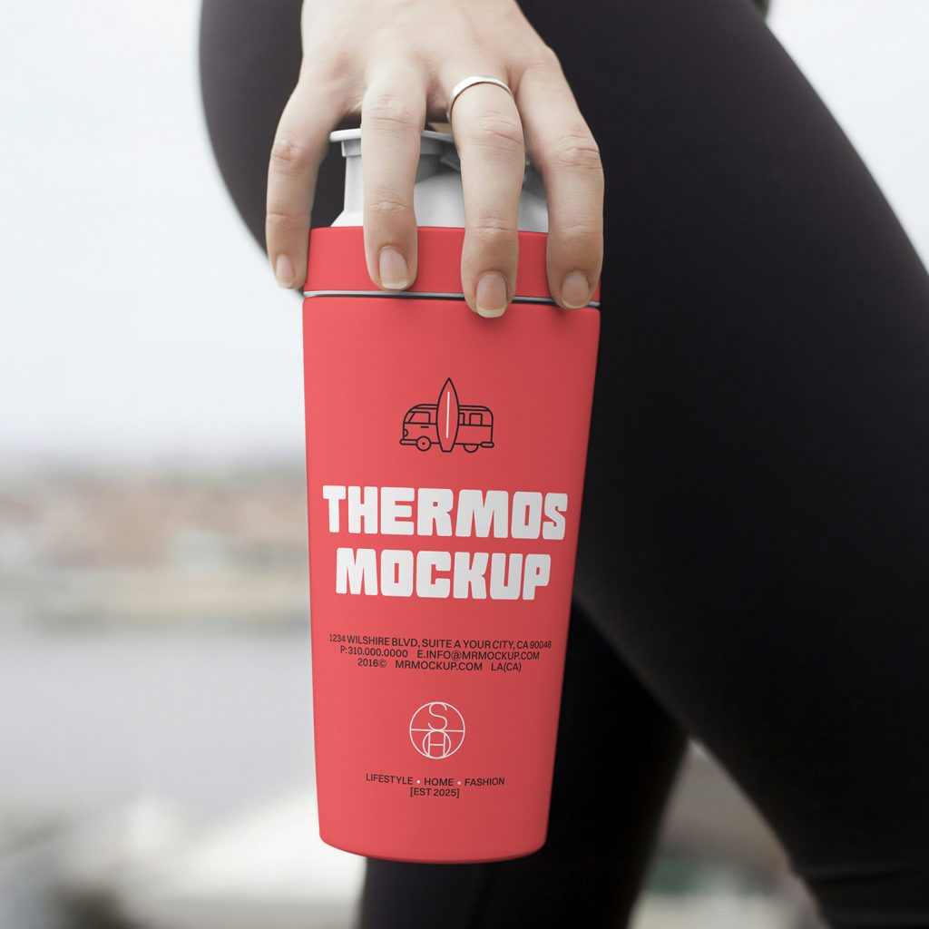 Front view of a red thermos mockup with white and black typography design held by a woman's hand.