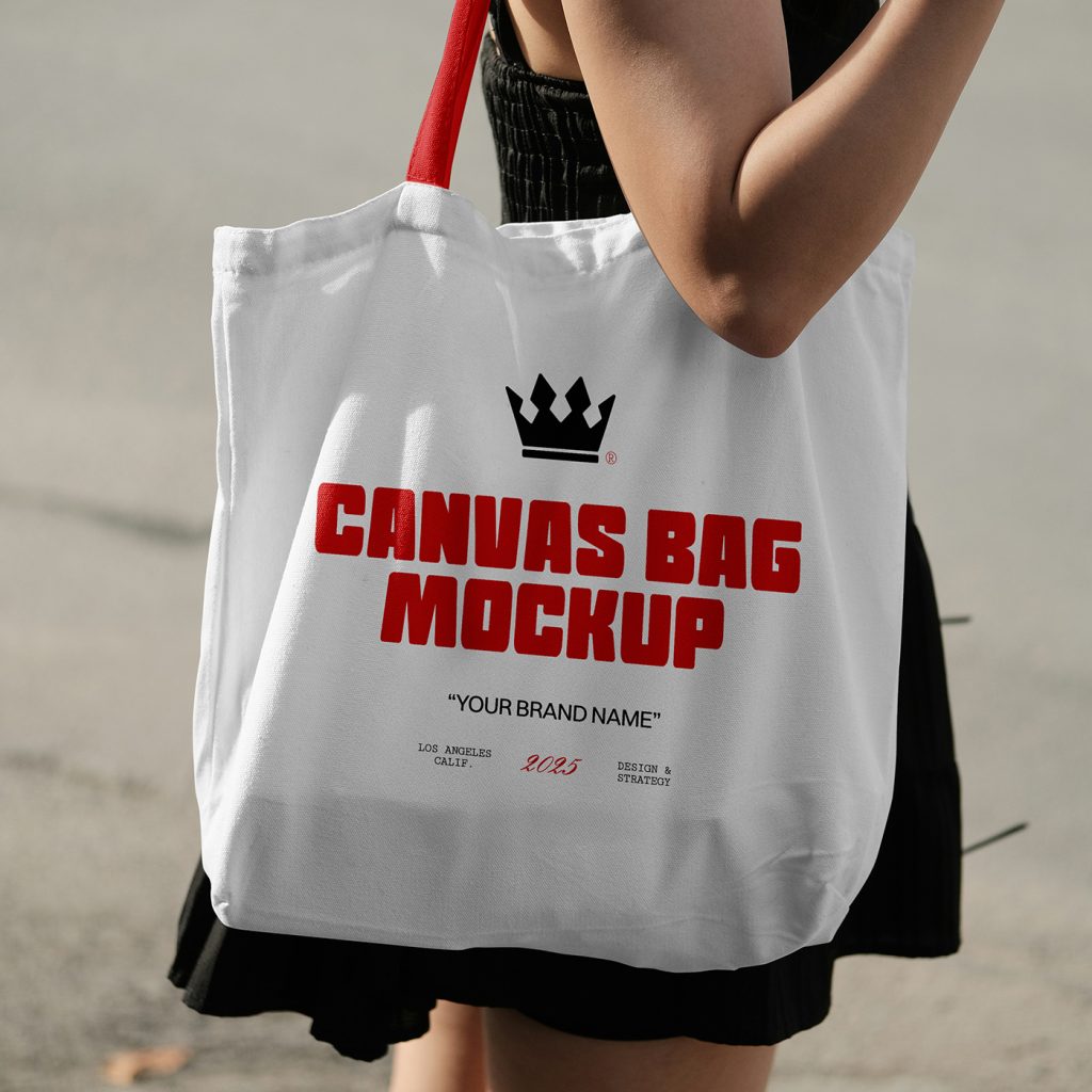 Front view of a white canvas bag mockup with a red handle worn by a woman on the streets.